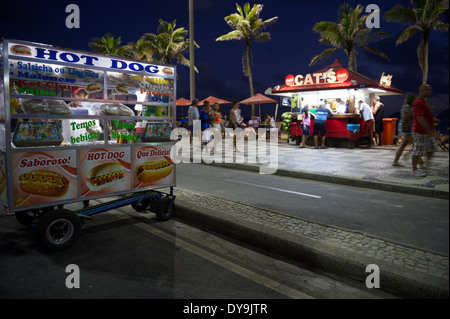 RIO DE JANEIRO, Brasilien - 19. Januar 2014: Pedestriands pass eine mobiler Hot Dog Stand vor der Strandkiosk in eine typische Szene Stockfoto