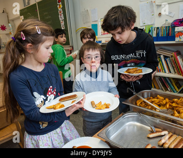 Nicht behinderte und behinderte Schüler (in diesem Fall ein Junge mit Down-Syndrom) haben Mittagessen zusammen in ihrem Klassenzimmer. Stockfoto