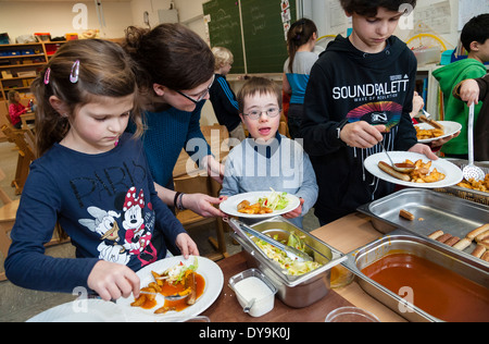 Nicht behinderte und behinderte Schüler (in diesem Fall ein Junge mit Down-Syndrom) haben Mittagessen zusammen in ihrem Klassenzimmer. Stockfoto