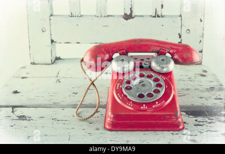 Roter Spielzeug Telefon auf alten leichten blauen Holzstuhl mit Vintage bearbeiten Stockfoto