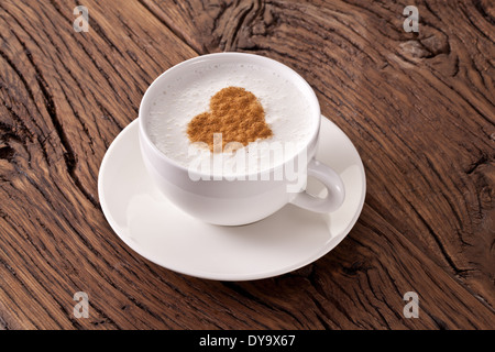 Tasse Cappuccino mit gemahlenem Zimt in Form von Herzen auf alten Holztisch. Ansicht von oben. Stockfoto