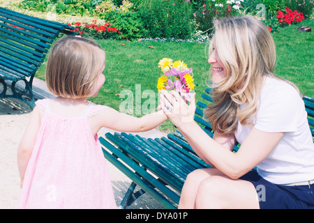 Kleines Mädchen präsentiert Mutter mit Blumenstrauß Stockfoto