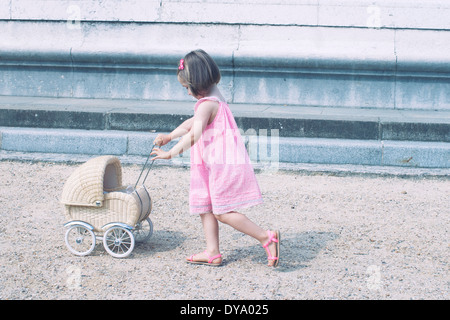 Kleines Mädchen Miniatur Kinderwagen schieben Stockfoto