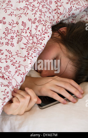 Frau schläft im Bett mit Smartphone in der hand Stockfoto