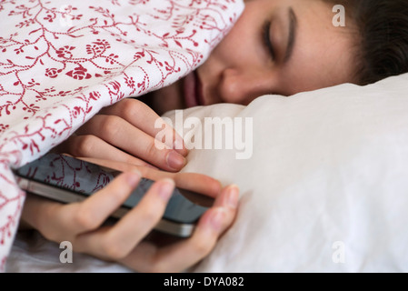 Frau schläft im Bett mit Smartphone in der hand Stockfoto