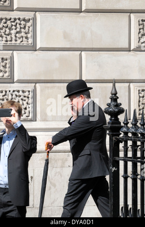 London, England, Vereinigtes Königreich. Stadt Gent eine Melone auf dem Handy auf der Straße Stockfoto