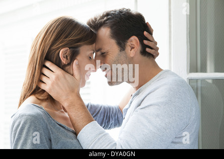 Paar kuscheln durch offene Fenster Stockfoto