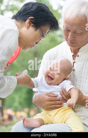 Asiatische chinesische Großeltern spielen mit Baby Enkel im Garten. Stockfoto