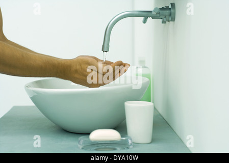 Die Hände des Mannes unter fließendem Wasser im Waschbecken, Seitenansicht Stockfoto