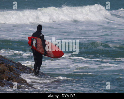 Surfer, die am Ende der Mole, Blick auf die Wellen, Bude, Cornwall, UK Stockfoto