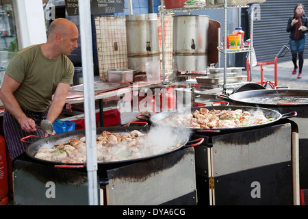 Mann kochen Huhn in großen Pfanne auf der Portobello Market in London W11 - UK Stockfoto