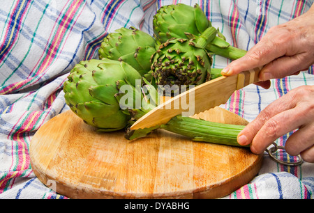 Artischocke auf Schneidebrett wird mit einem Bambus Messer geschnitten Stockfoto