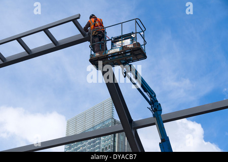 Stahl-Aufrichter stehend ein Access-Plattform (Hubarbeitsbühne) auf eine Construction Site, First Street, Manchester, England, UK Stockfoto