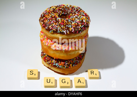 Geeiste Krapfen auf einem weißen Hintergrund mit Scrabble Buchstaben buchstabieren des Wortes Zuckers Stockfoto