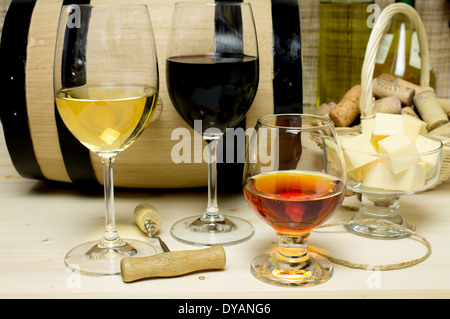 Rot- und Weißwein in Gläser Schnaps. Auf dem Hintergrund eines Fasses und Weinkorken Korb Schale mit Käse und eine Flasche gewinnen Stockfoto