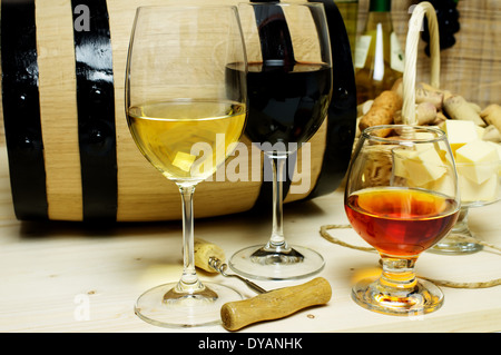 Rot- und Weißwein in Gläser Schnaps. Auf dem Hintergrund eines Fasses und Weinkorken Korb Schale mit Käse und eine Flasche gewinnen Stockfoto