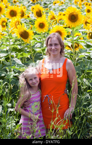 lächelnde kaukasischen Frau und kleine Mädchen stehen auf Sonnenblumen Feld Hintergrund Stockfoto