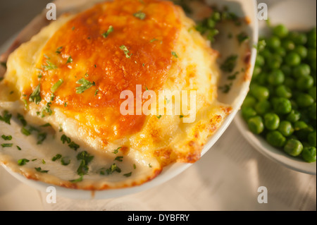 Fisch und Kartoffeln Kuchen mit einem Käse-Topping und eine Beilage Erbsen. Stockfoto