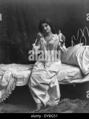 Frau sitzend auf Bett und Löffel Einnahme der Medizin, um 1910 Stockfoto