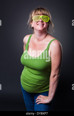 Glückliche junge schwangere Frau im Studio - dunklen Hintergrund Stockfoto