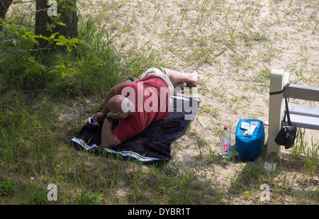 Mann mittleren Alters am Strand mit Blick auf Telefon allein Stockfoto