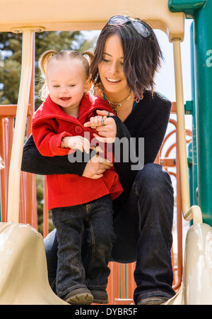 Schöne junge Mutter auf Park Spielplatz mit liebenswert, niedlich 16 Monate Baby Girl Spielen Stockfoto