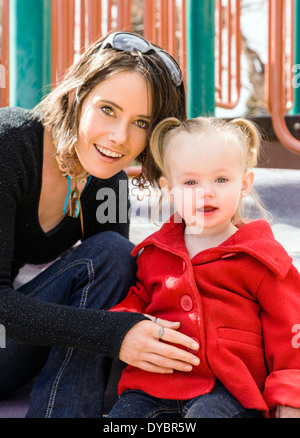 Schöne junge Mutter auf Park Spielplatz mit liebenswert, niedlich 16 Monate Baby Girl Spielen Stockfoto