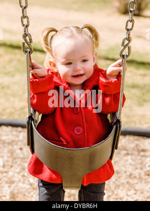 Niedlich, liebenswert 16 Monat Mädchen schwingen auf einem Park-Spielplatz Stockfoto