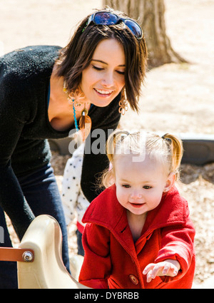 Schöne junge Mutter auf Park Spielplatz mit liebenswert, niedlich 16 Monate Baby Girl Spielen Stockfoto