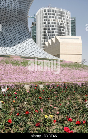 Basis des Curvelinear Museo Soumaya trifft Boden von blühenden Blumen, wie es Oberteil & Sägezahn Dach des Museo Jumex frames Stockfoto