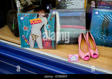 Schallplatten und ein paar rosa Schuhe, Teil eines Krebs-Forschung-Charity-Shop-Fensters angezeigt. Stockfoto