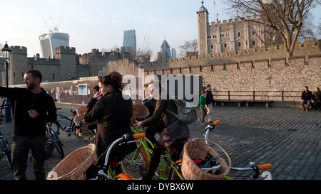 Fahrradtour für Gruppen und Fahrradverleih mit Korbkörben halten an, um über die Themse am Tower of London in England zu blicken Stockfoto