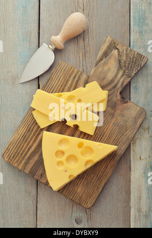 Käse mit großen Löchern und Messer auf Holzbrett Stockfoto