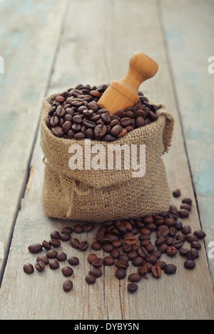 Plünderung Kaffeebohnen mit Schaufel auf hölzernen Hintergrund closeup Stockfoto