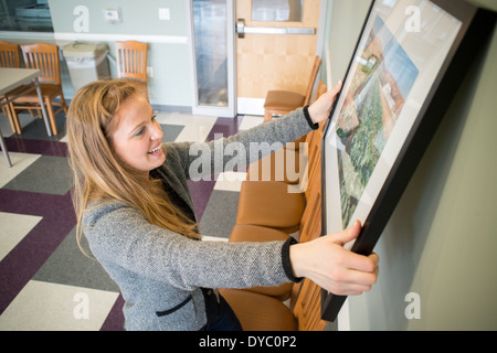 Junge Frau hängen Fotografien an Wand Stockfoto