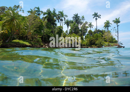 Tropischen Insel mit üppiger Vegetation und einem Boot am Liegeplatz Boje, gesehen von der Wasseroberfläche des karibischen Meeres, Panama Stockfoto