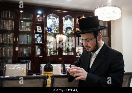 London, UK - 13. April 2014: ein Mitglied der jüdischen Gemeinschaft von Stamford Hill nutzt sein Handy in seinem Haus in der Nacht vor Pessach. Bildnachweis: Piero Cruciatti/Alamy Live-Nachrichten Stockfoto