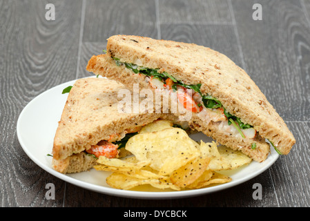 Krebse und Garnelen-Sandwich mit Rucola (Aragula) und Kartoffelchips auf einem weißen Teller - Studio gedreht Stockfoto