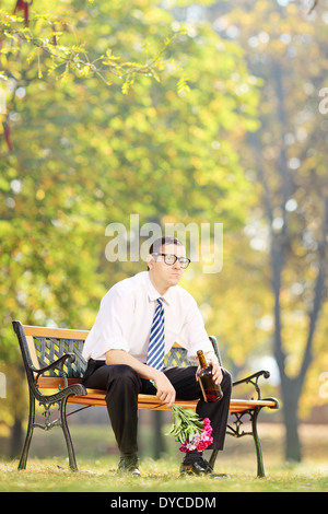 Trauriger Mann Alkohol trinken und Blumen im Freien halten Stockfoto