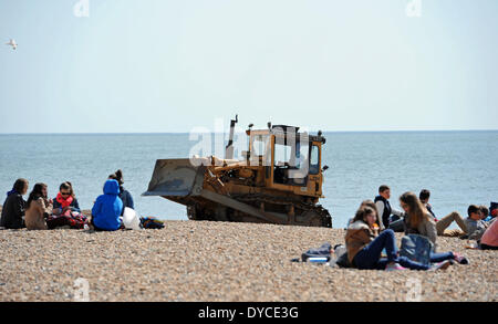 Arbeiter arbeiten einen mechanischen Bagger neben Besucher genießen die schönen warmen Frühlingswetter auf Brighton beach Stockfoto