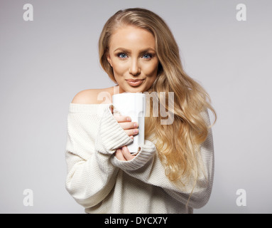 Porträt der nette junge Frau mit Pullover Kaffee trinken. Schöne kaukasischen weibliches Modell mit Tasse heißen Kaffee. Stockfoto