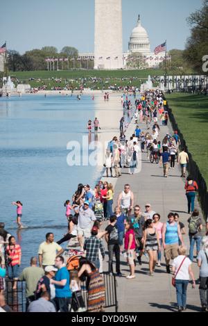 Besucher nutzen Sie warme Wetter, die neu renovierten Lincoln Memorial Reflecting Pool auf der National Mall in Washington DC zu genießen. Im Hintergrund ist die Basis des Washington Monument, die Kuppel der US Capitol Building in der Ferne. Stockfoto