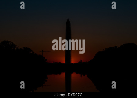 Die Sonne unter dem Horizont wirft eine Morgendämmerung leuchten hinter der Basis des Washington Monument. Blick von Lincoln Memorial Reflecting Pool. Diese Aufnahme wurde während der Herbstanfang aufgenommen, wenn die Sonne steigt direkt nach Osten und daher reiht sich mit der National Mall. Stockfoto