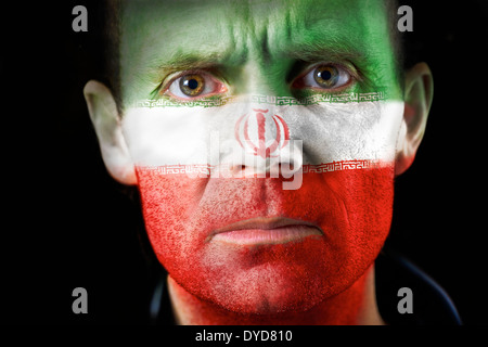 Ein intensiver Blick von einem Mann mit ihrem Gesicht gemalt mit der iranischen Flagge. Stockfoto