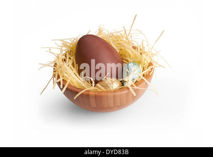 Ein hölzernes Schüsselchen Schokoladeneier eingewickelt in farbigen Alufolie auf einem weißen Hintergrund. Stockfoto