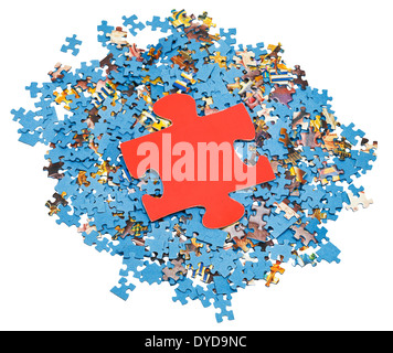 große rote Einteiler auf Haufen von zerlegten kleine blaue Puzzles isoliert auf weißem Hintergrund Stockfoto