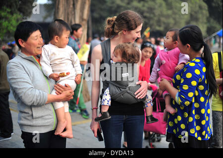 Peking, China. 14. April 2014. Whitney C. Johnson, Direktor der Fotografie des New Yorker, plaudert mit einem chinesischen Kind halten Sie ihr Baby 11 Monate im Sommerpalast in Peking, Hauptstadt von China, 14. April 2014. Johnson war in Peking, als Richter des 10. China International Press Photo (CHIPP) Wettbewerbs dienen. © Sun Ruibo/Xinhua/Alamy Live-Nachrichten Stockfoto