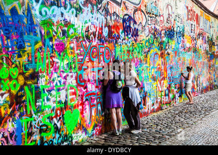 Zwei weibliche Touristen hinzufügen Graffiti an der John-Lennon-Mauer in Prag. Stockfoto