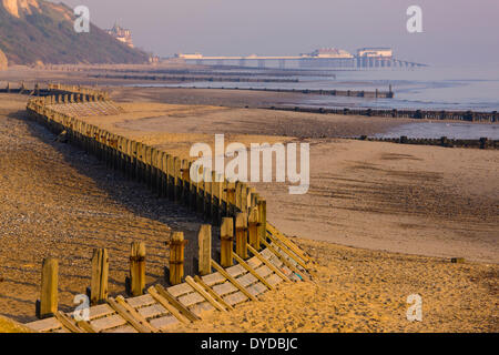 Wellenbrecher im Overstrand Beach mit Cromer Pier in der Ferne. Stockfoto