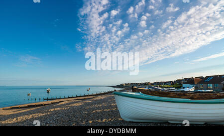 Blick entlang Selsey Strand bei Sonnenuntergang mit kleinen Booten auf dem Kies ausgearbeitet. Stockfoto